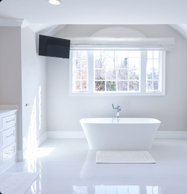 A White Bathroom With A Bathtub And A Tv