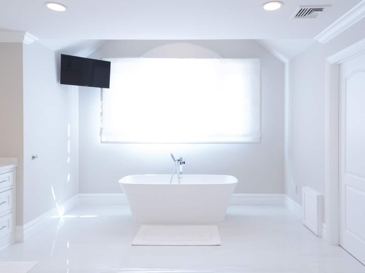 A White Bathroom With A Bathtub And A Tv